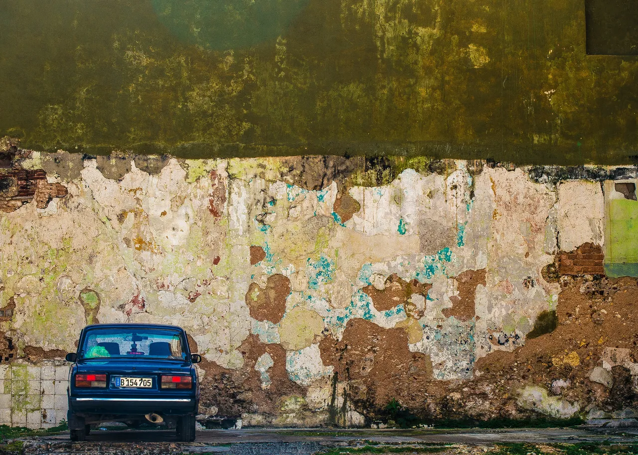 Car parked against a destroyed wall. Photo by Delaney Turner.